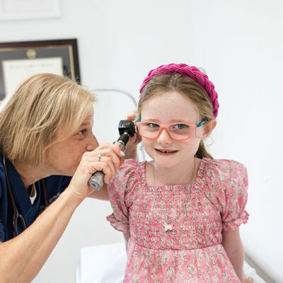 Doctor Mindy Gallagher doing an ear check for a young girl who sits patiently