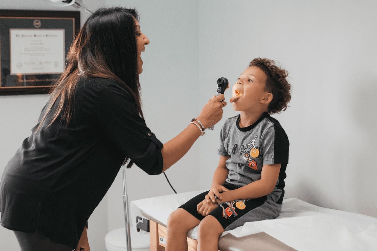 Dr. Sonia Patel checking the inside of a child's mouth with an Otoscope